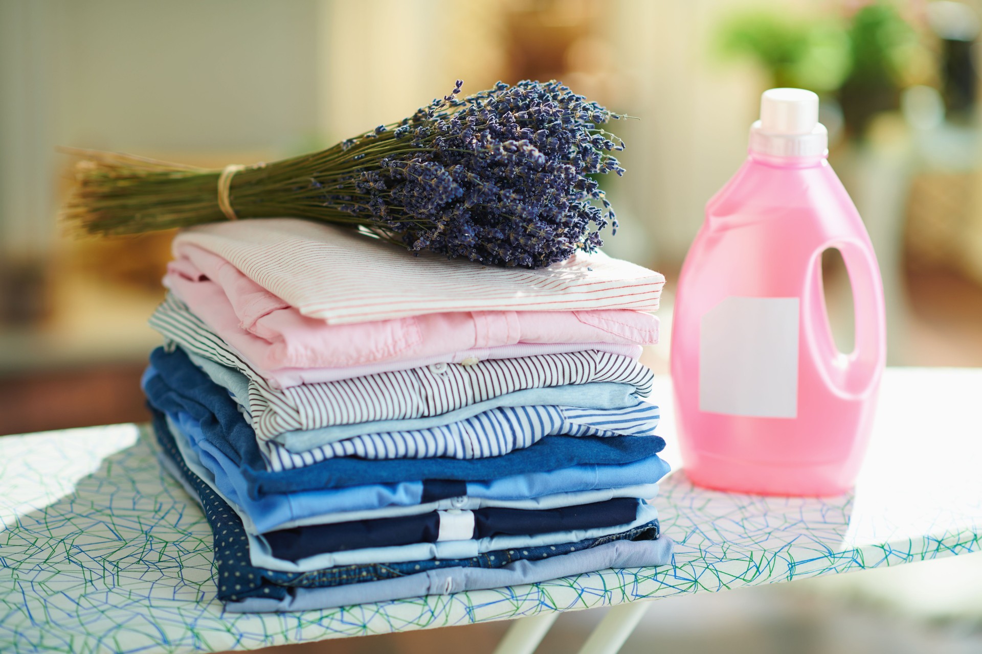 pile de vêtements, adoucisseur et bouquet de lavande sur la planche à repasser