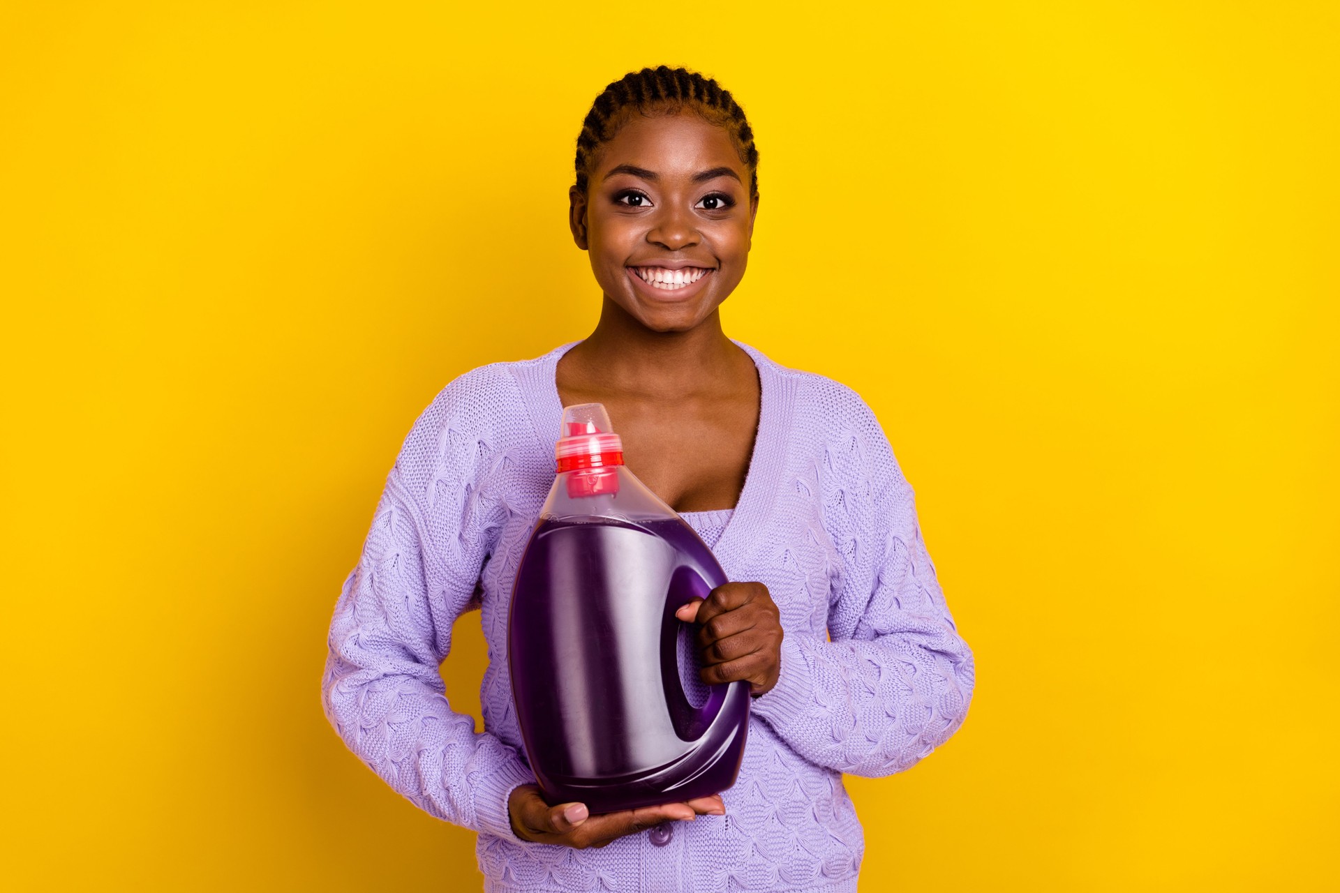 Portrait of positive nice lady arms hold demonstrate laundry detergent bottle isolated on yellow color background